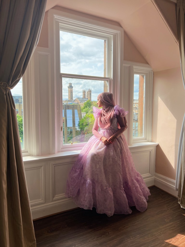 This is a decorative photo of Annie Mirza, The Annie M, sitting in a princess dress by a window.